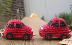 two small red cars are sitting on a wooden table next to a keychain