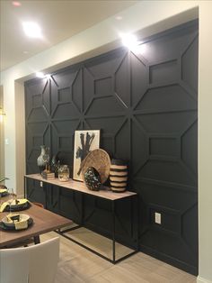 a dining room table and chairs in front of a black wall with geometric designs on it