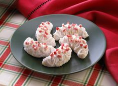 four cookies with white frosting and red sprinkles on a green plate