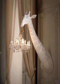 a giraffe lamp hanging from the side of a wall next to a chandelier