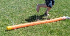 a young boy is playing in the grass with an orange tube that has been thrown to him