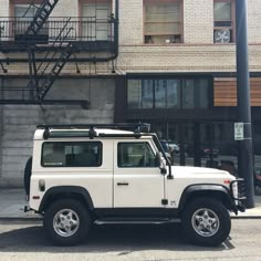 a white land rover is parked in front of a brick building with stairs on the side