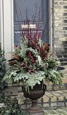 a planter filled with red berries and greenery sitting on the front step of a house