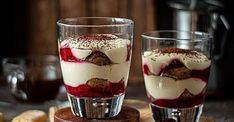 two glasses filled with desserts sitting on top of a wooden table next to each other