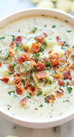 a white bowl filled with potato soup and garnished with bacon