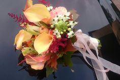 a bouquet of flowers is sitting on the hood of a car with a ribbon tied around it