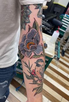 a man with a bird and flower tattoo on his arm