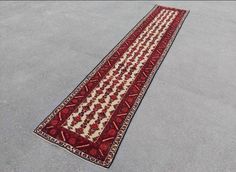 a red and white runner rug laying on the ground in front of a parking lot