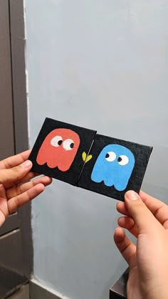 two people holding up small cards with faces on them