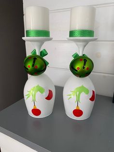 two white vases with green and red designs on them sitting on a counter top