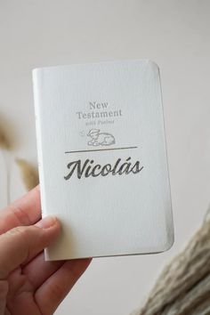 a person holding up a white book with the word nicholas written in cursive writing