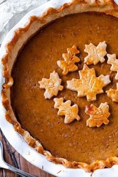 a pie is decorated with small leaves and snowflakes on the top, sitting on a wooden table