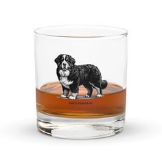 a glass with a black and white dog on the side, in front of a white background