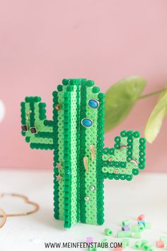 a cactus made out of legos sitting on top of a table next to some beads