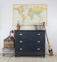 a blue dresser with a map on the wall above it and two paddles leaning against it