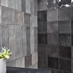 a white vase sitting on top of a table next to a black tiled bathroom wall