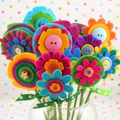 a vase filled with colorful felt flowers on top of a polka dot tablecloth covered wall