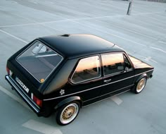 a small black car parked in a parking lot