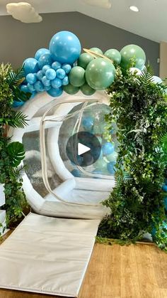 a room filled with balloons and greenery on the wall next to a wooden floor