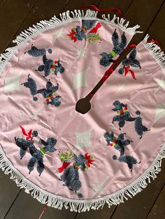 a pink and white table cloth with poodles on it is sitting on a wooden floor