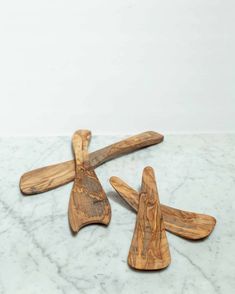 three wooden spatulas sitting on top of a white marble counter next to each other