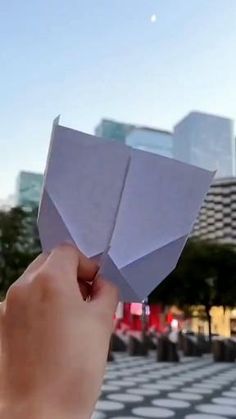 someone is holding an origami piece in front of a cityscape with skyscrapers