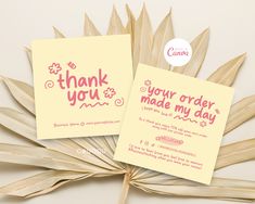 two thank you cards sitting on top of a palm fronder next to each other