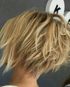 the back of a woman's head with short blonde hair in front of a gray background