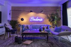 a living room filled with furniture and a neon sign on the wall above it's windows