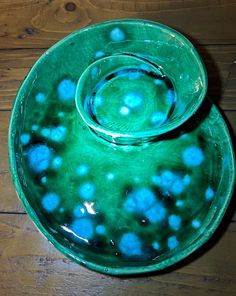 a green bowl sitting on top of a wooden table