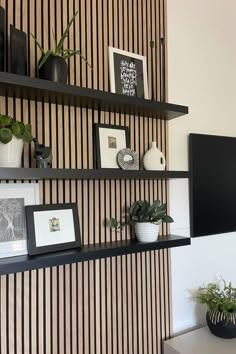 the wall is decorated with black and white striped wallpaper, potted plants and framed pictures