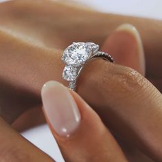 a woman's hand with a diamond ring on her finger and the other hand holding it