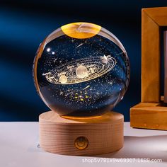 a glass globe with an image of the solar system in it on a wooden stand