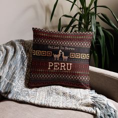 a decorative pillow sitting on top of a couch next to a potted palm tree