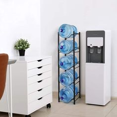 a water dispenser next to a white cabinet with blue bottles on it