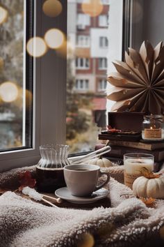 a coffee cup and saucer sitting on a table next to a window with lights in the background