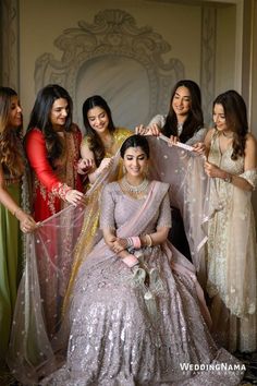 a group of women standing next to each other in front of a wall holding dresses