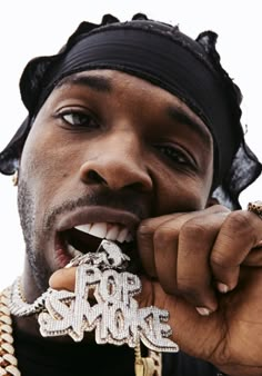 a man wearing a black hat and holding a gold chain around his neck with the word love spelled on it