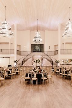 a large hall with tables and chairs set up for a formal function in front of chandeliers