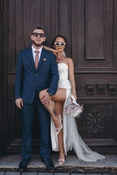 a man in a suit and tie standing next to a woman wearing a white dress