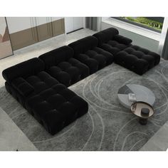 a black sectional sofa sitting on top of a gray rug