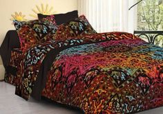 a bed covered in a colorful comforter next to a window