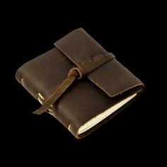 an open brown leather book with a tie around the cover and two pages on each side