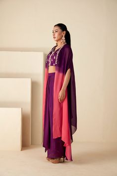 Elevate your festive wardrobe with the Radiant Orchid Ombre Ensemble a fusion of elegance and modern flair. This set features a pre-draped skirt and a hand-embroidered blouse, complemented by an airy ombre cape that transitions from rich purple to delicate pink. Traditional Drape Purple Georgette Palazzo Set, Purple Georgette Palazzo Set With Traditional Drape, Silk Fusion Set With Traditional Drape, Fusion Silk Set With Traditional Drape, Navratri Georgette Anarkali Set With Cape Sleeves, Navratri Georgette Dupatta With Cape Sleeves, Festive Fusion Style Pre-draped Georgette Saree, Festive Fusion Silk Sets, Festive Fusion Style Silk Sets