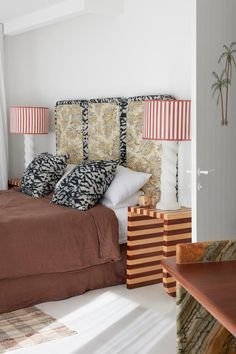 a bed with two lamps on either side of the headboard and pillows in front of it