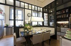 a dining room table with chairs and a cake on top of it in front of windows