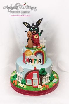 a three tiered cake with an animal and rainbow theme on it's side