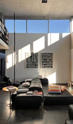 a living room filled with black furniture and large windows overlooking the cityscape outside