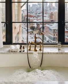 a bathtub in front of a window with a view of the city and buildings