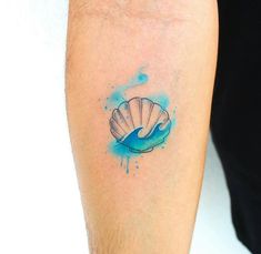 a person with a tattoo on their arm that has a blue watercolor shell on it